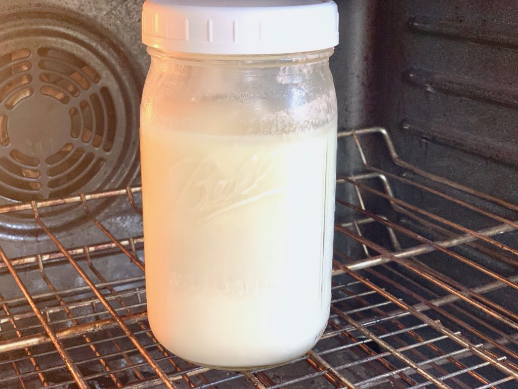a quart size mason jar with yogurt in oven
