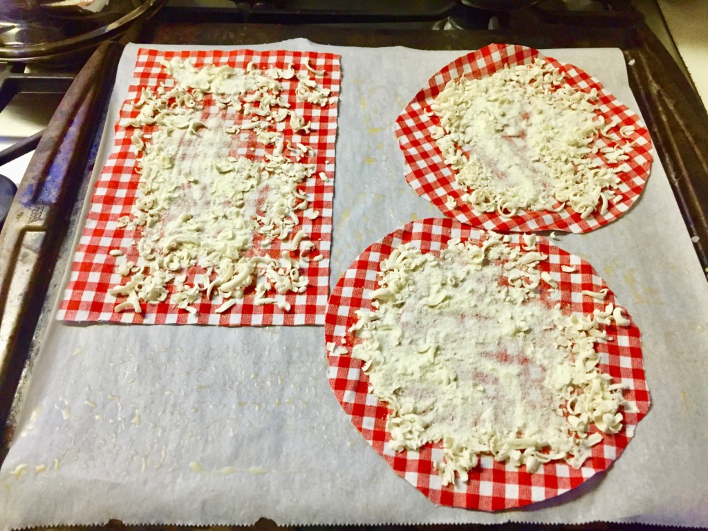 three pieces of fabric on parchement paper lined cookie sheet with beeswax, resin, and jojoba oil on them