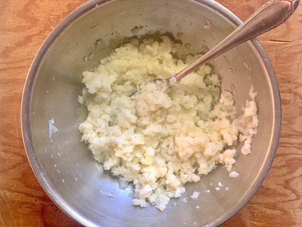 steamed and mashed cauliflower in bowl with fork