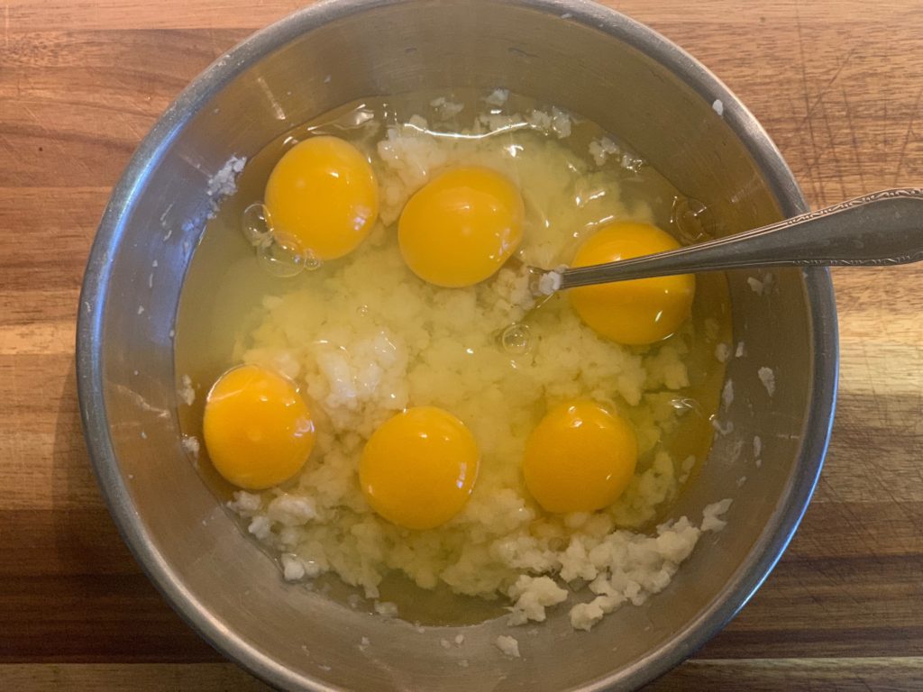 mashed cauliflower in bowl with 6 cracked eggs