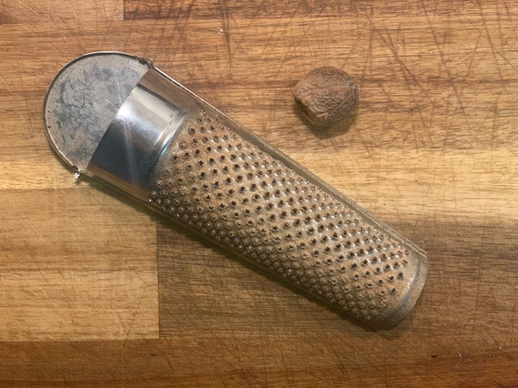 nutmeg grater with nutmeg on cutting board