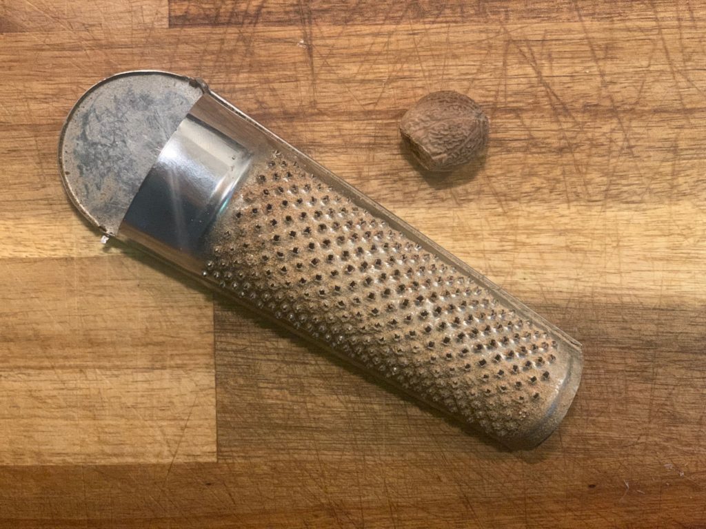 nutmeg grater with nutmeg on cutting board
