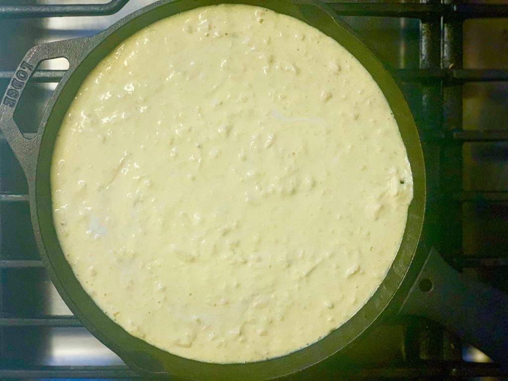 cheese egge mixture in cast iron skillet on stove