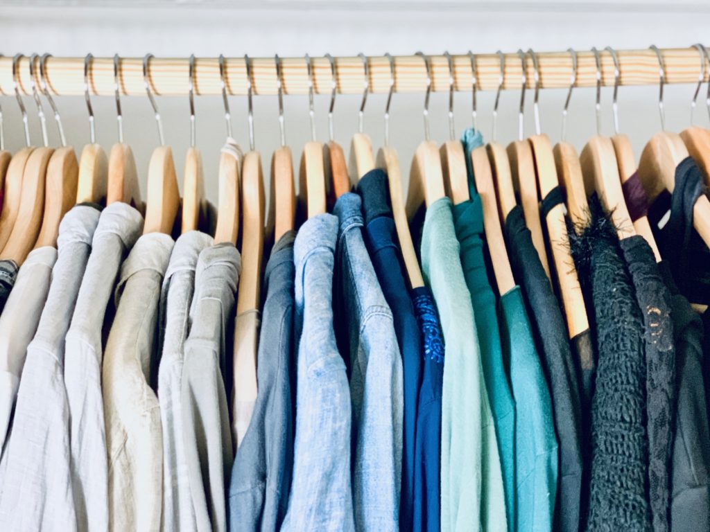 shirts of various color organized on wooden hangers