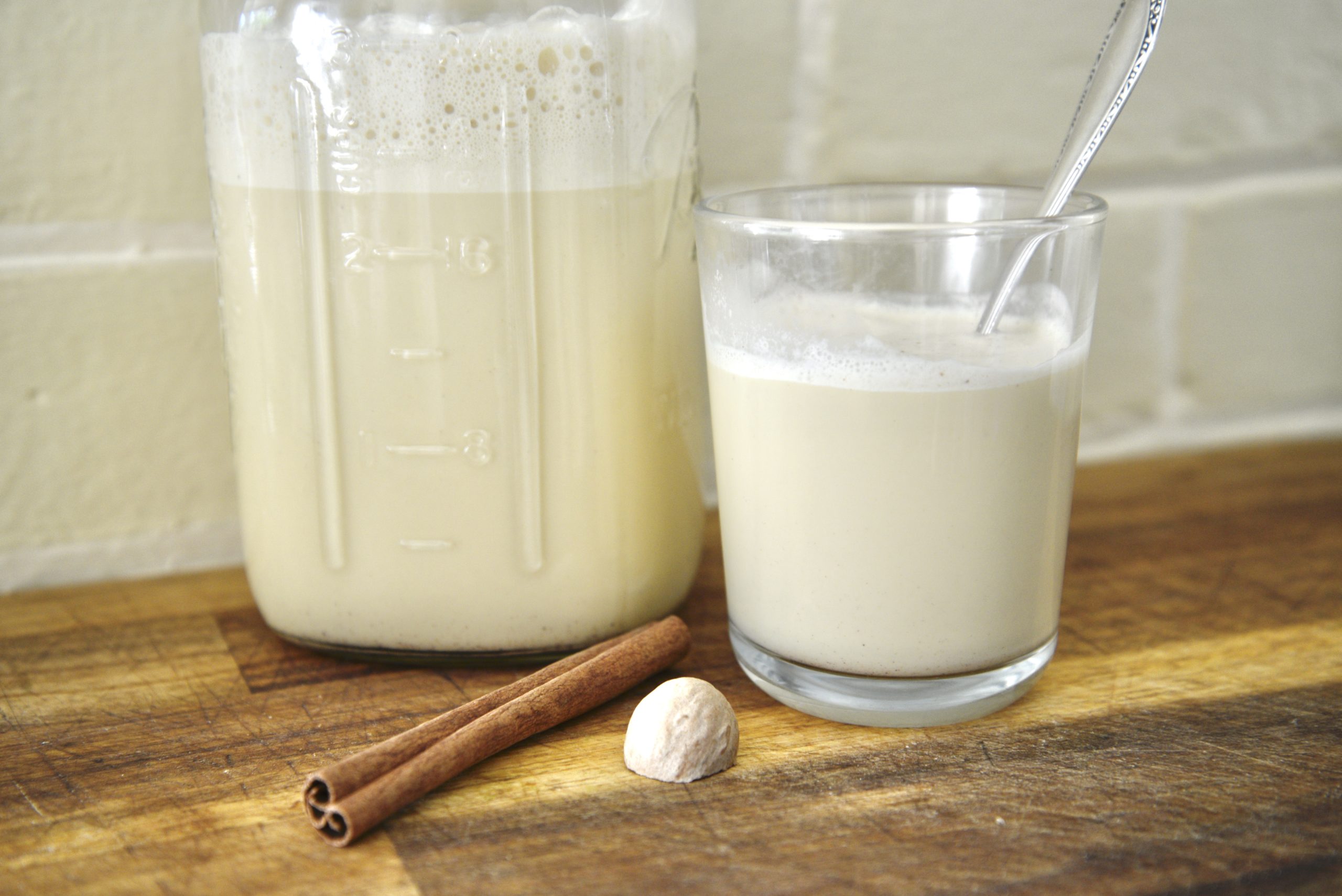 jar and glass with eggnog with cinnamon stick and nutmeg
