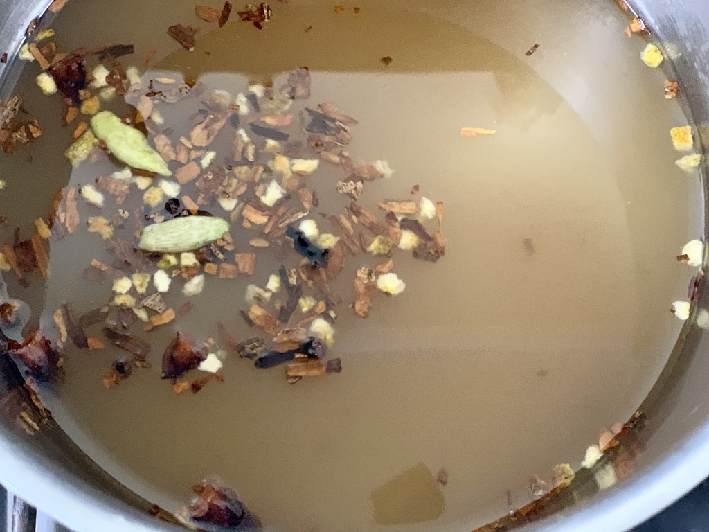 mulling spices in apple cider in stainless steel pot