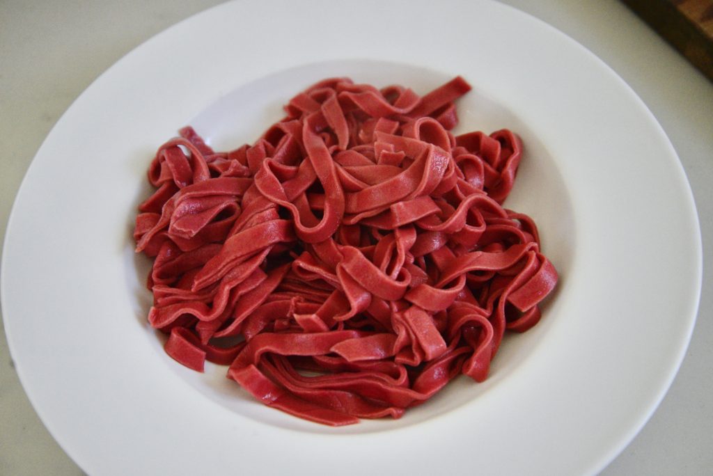 finished homemade beet pasta on white plate