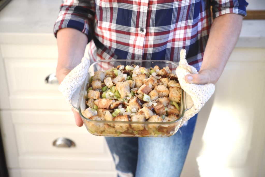woman holding thanksgiving stuffing in a glass dish